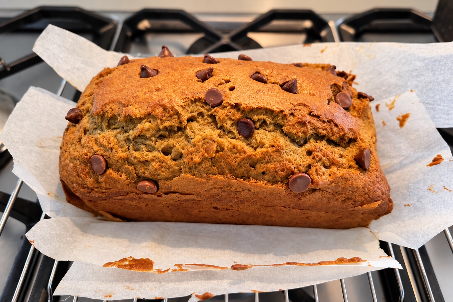 Our golden banana bread loaf with chocolate chips, cooling on baking paper.