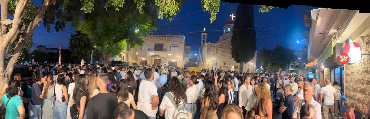 An evening gathering outside a church in Maghdoucheh around the Feast of Mary