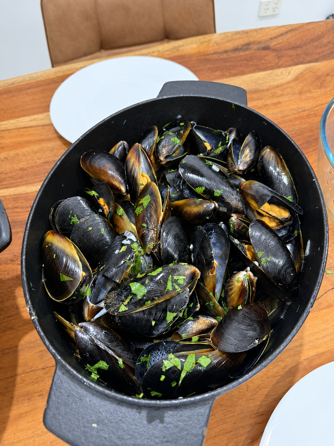 Moules Marinière served in a black pot with parsley