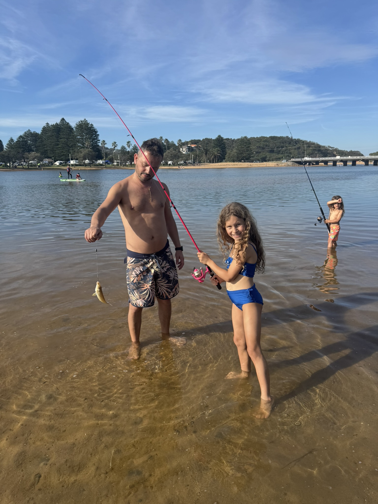 Daniel fishing with the children in the shallow water on a sunny Sydney day